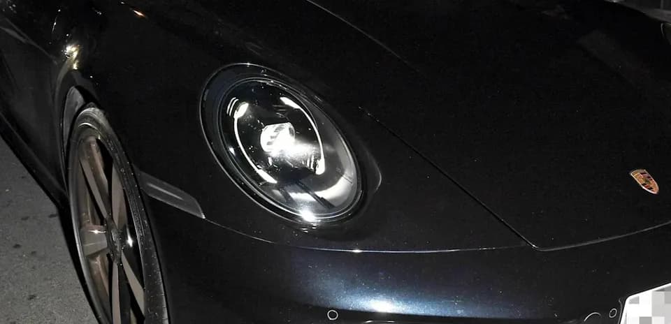 Dos hombres sentados en un Porsche negro