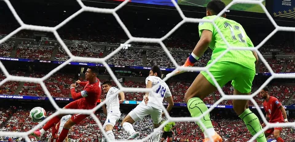Jugador rematando mientras el portero observa