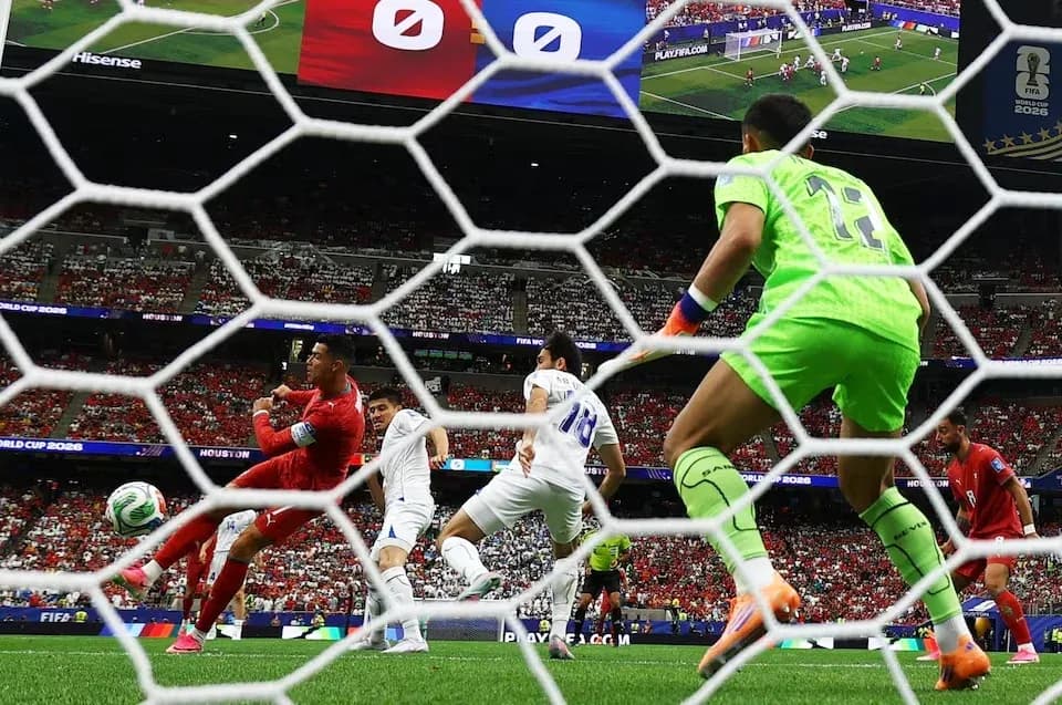 Jugador rematando mientras el portero observa