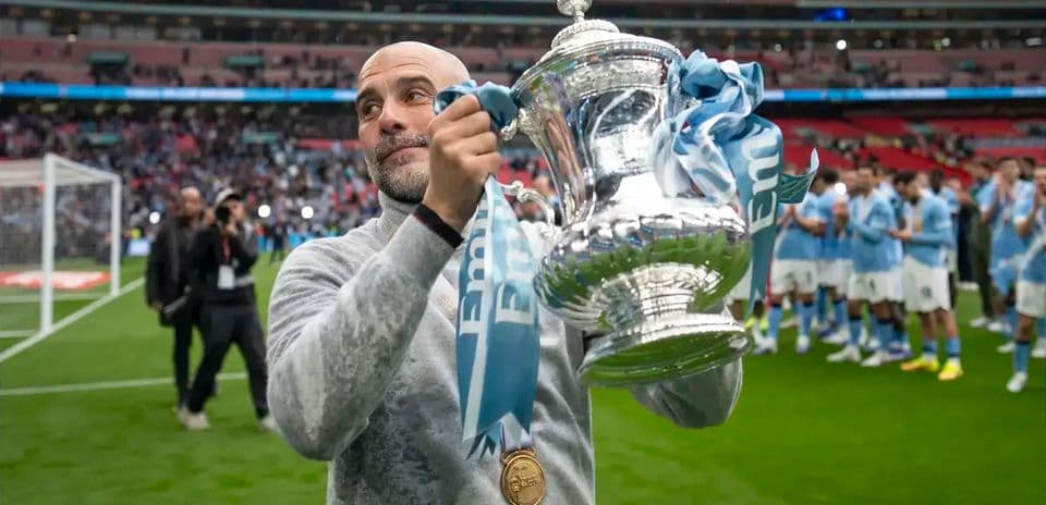 Entrenador levantando trofeo en Wembley tras victoria