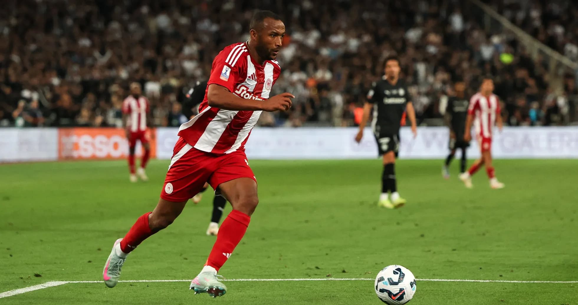 Jugador de Olympiacos corriendo hacia el balón en el campo
