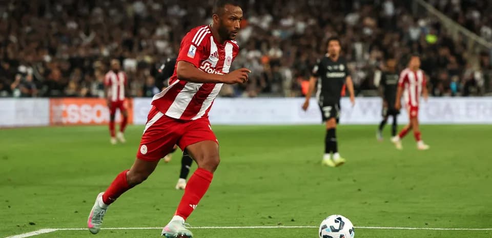 Jugador de Olympiacos corriendo hacia el balón en el campo