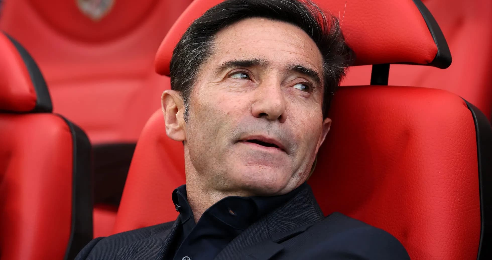 Entrenador sentado en banquillo rojo durante el partido