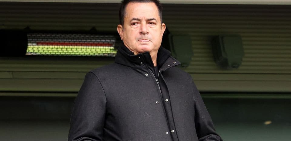 Hombre en abrigo negro observando desde una tribuna