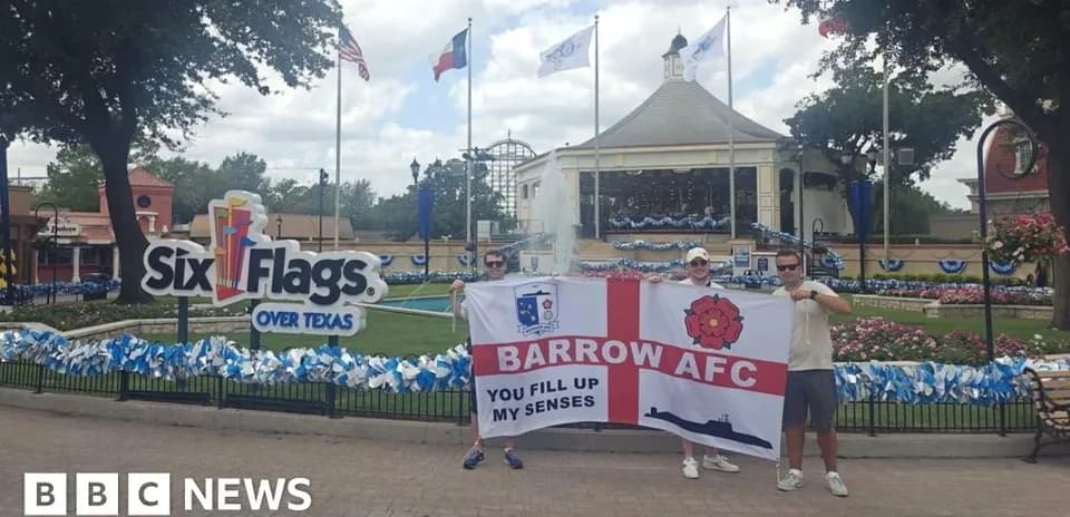 Dos personas sosteniendo bandera de Barrow AFC en parque