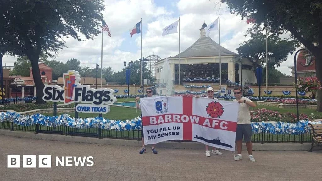 Dos personas sosteniendo bandera de Barrow AFC en parque