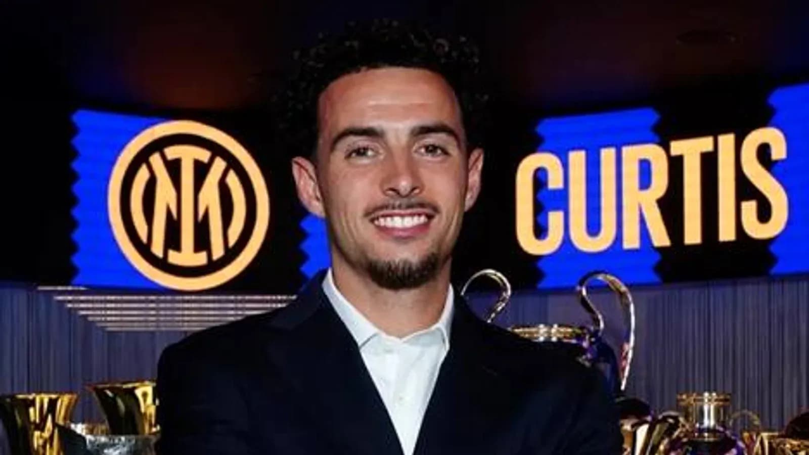 Jugador sonriente junto a trofeos de Inter