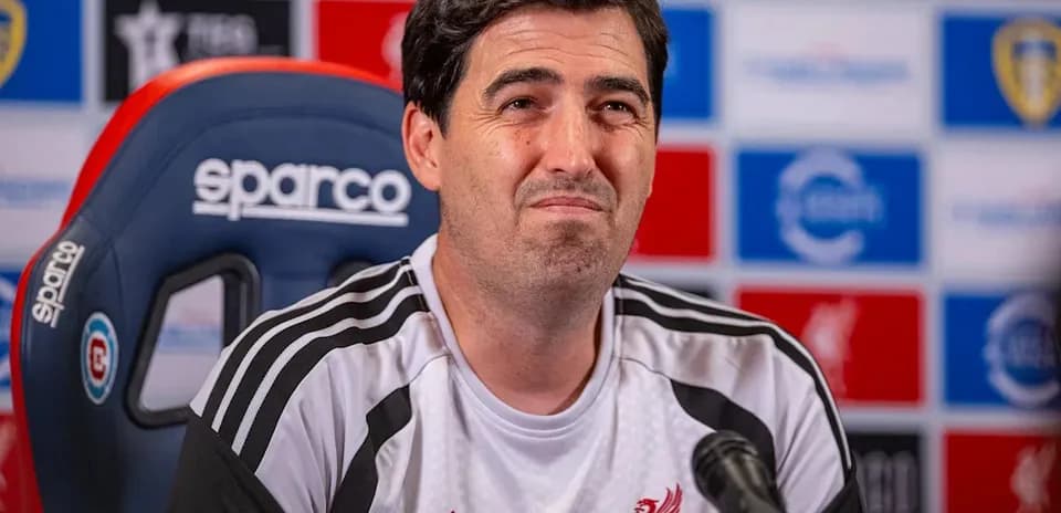 Entrenador en conferencia de prensa con logotipo de Liverpool