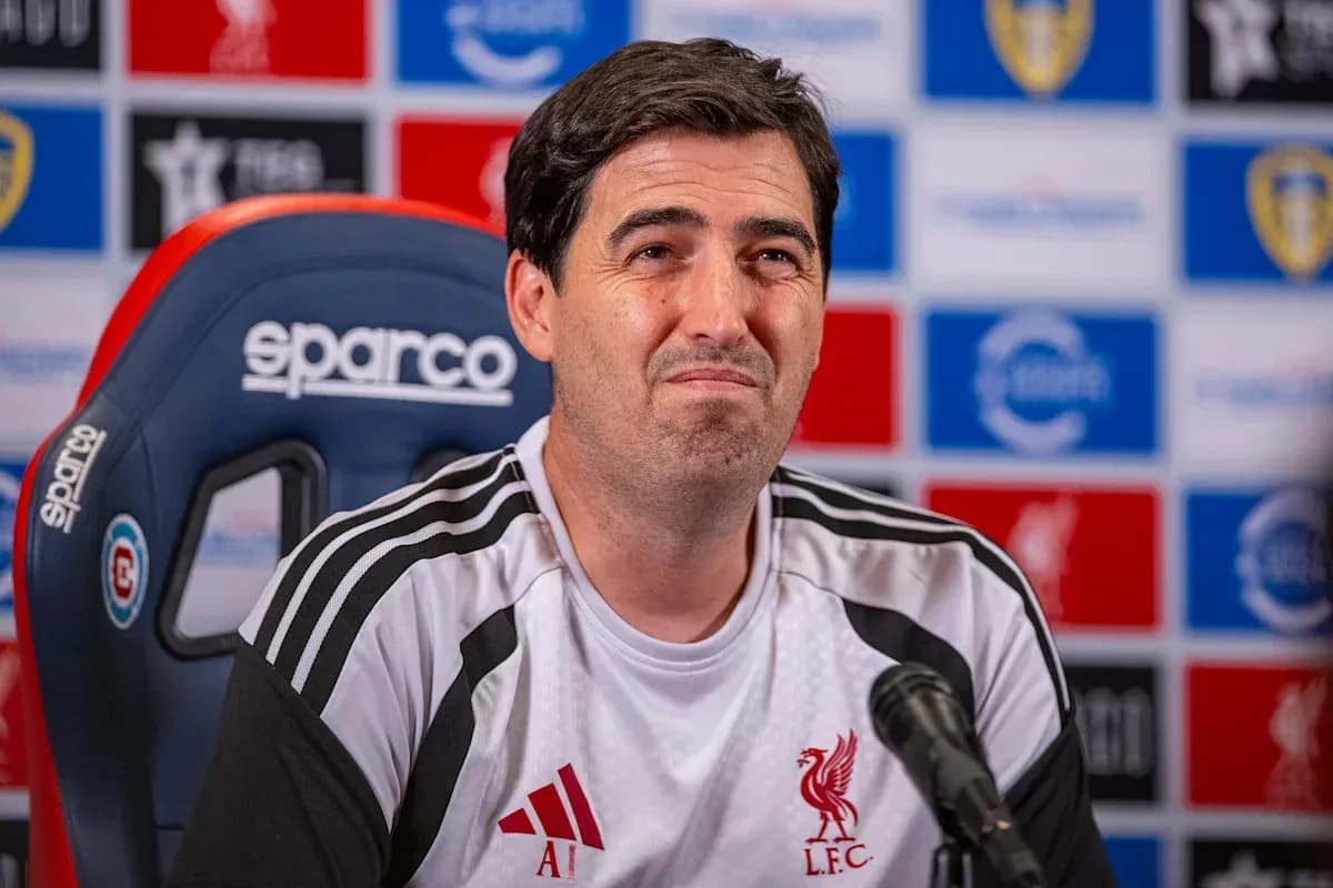 Entrenador en conferencia de prensa con logotipo de Liverpool