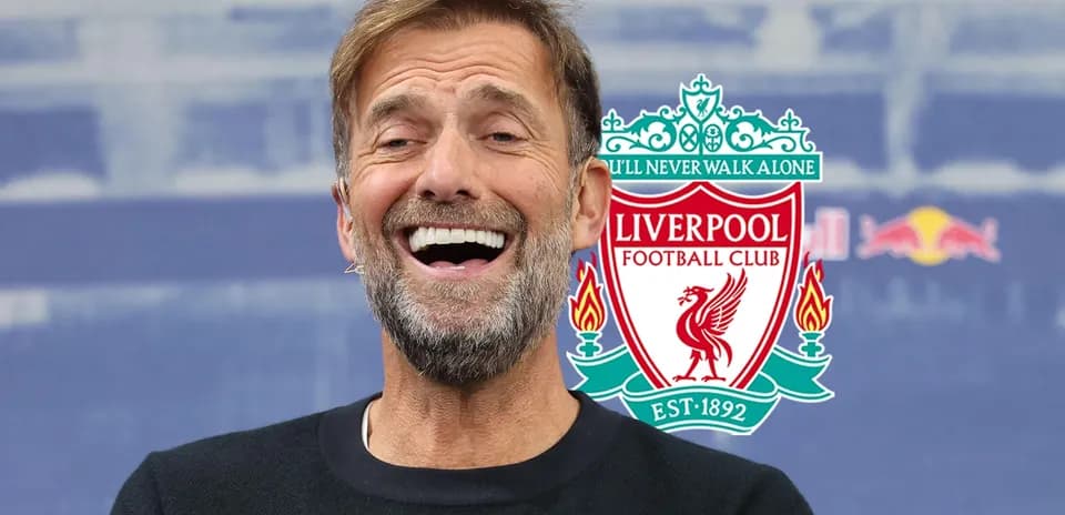 Entrenador sonriendo con logo de Liverpool de fondo