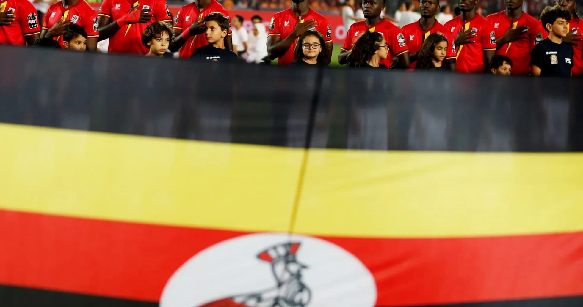 Jugadores de Uganda alineados con bandera nacional