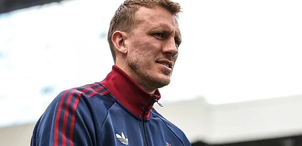 Jugador con chaqueta del equipo en el estadio