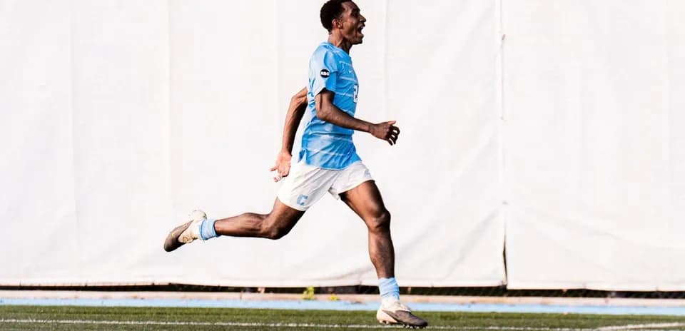 Jugador corriendo en campo de fútbol celebrando gol