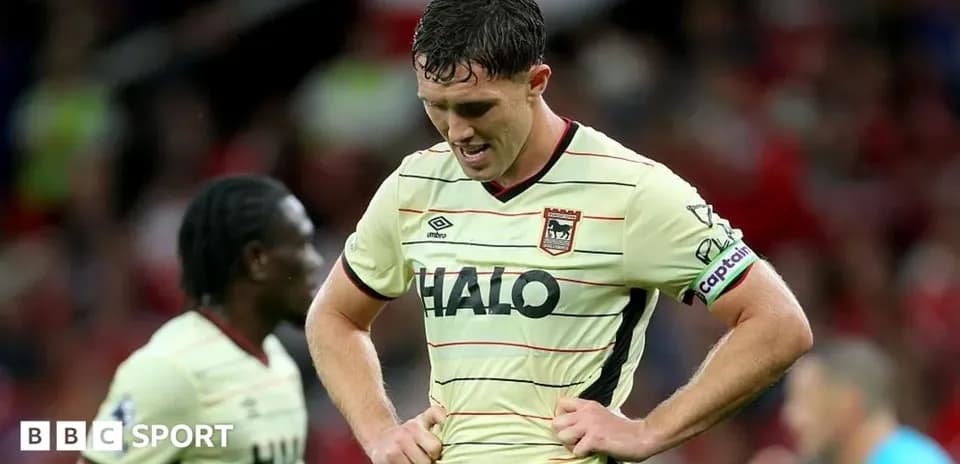 Jugador con camiseta de visitante, cabeza agachada en el campo