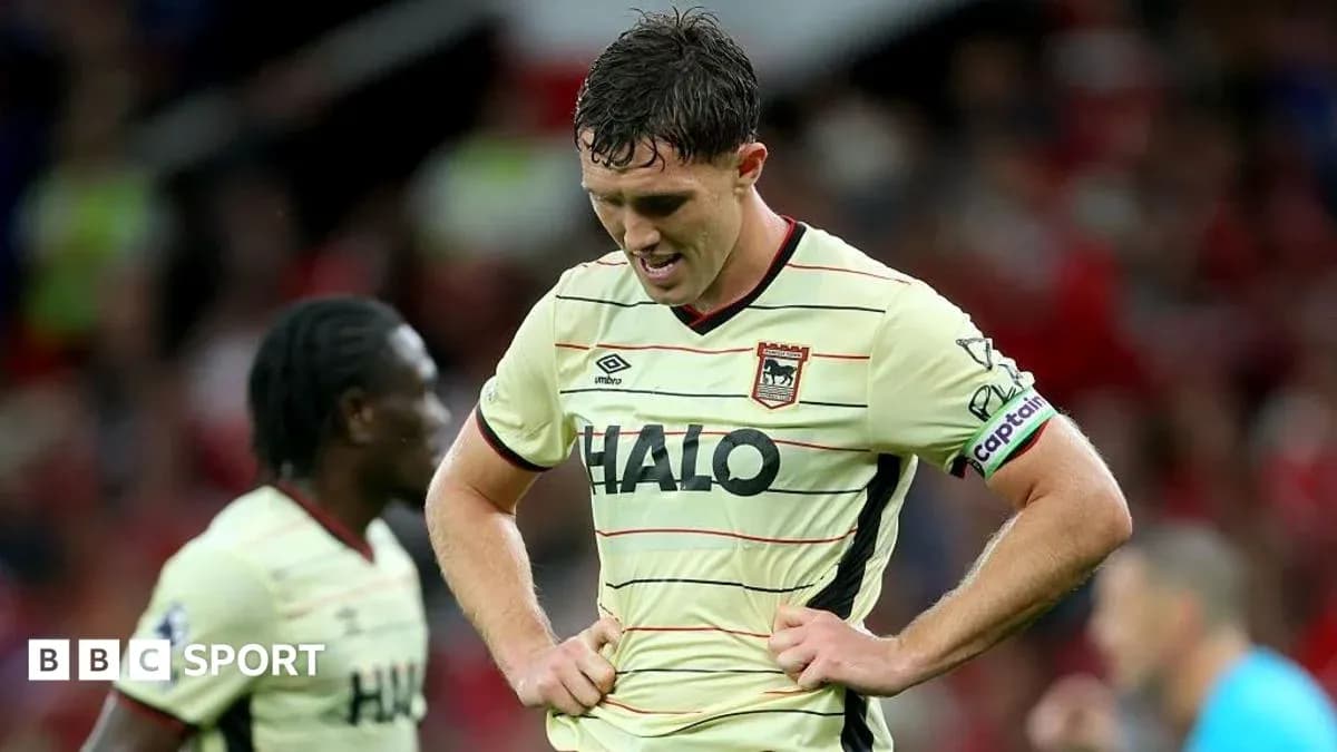 Jugador con camiseta de visitante, cabeza agachada en el campo