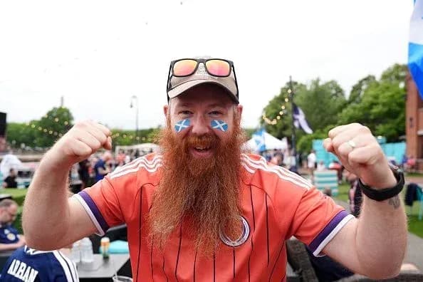 A fan celebrating with Scottish flags on face