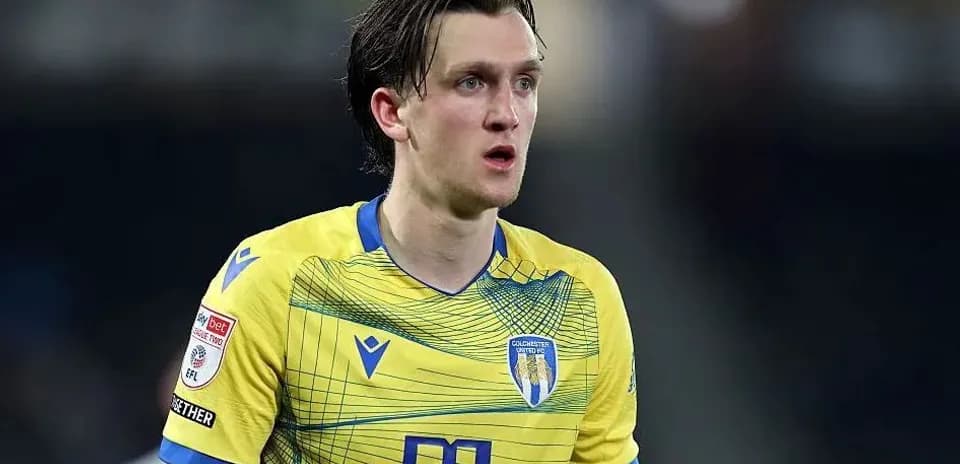 Jugador de Colchester United en uniforme amarillo durante partido