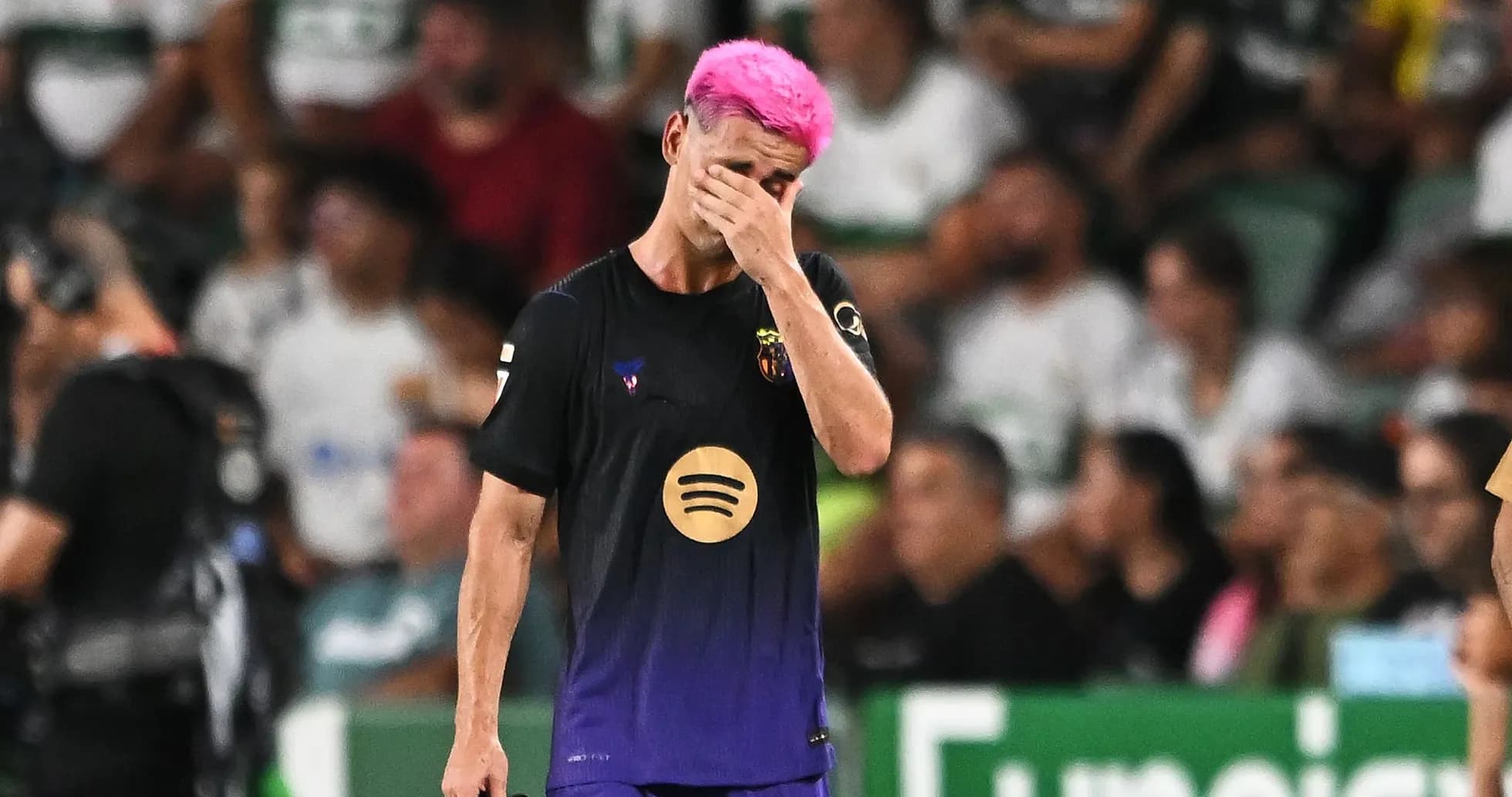 Jugador con cabello rosa cubriendo su rostro en el campo