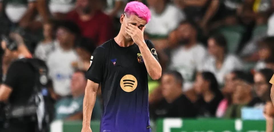 Jugador con cabello rosa cubriendo su rostro en el campo