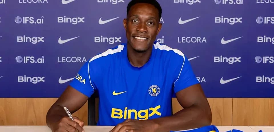 Jugador firmando contrato en mesa con camiseta