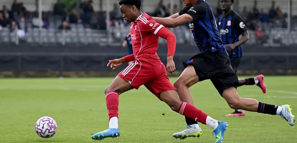 Jugador de Liverpool corriendo mientras es marcado por oponente
