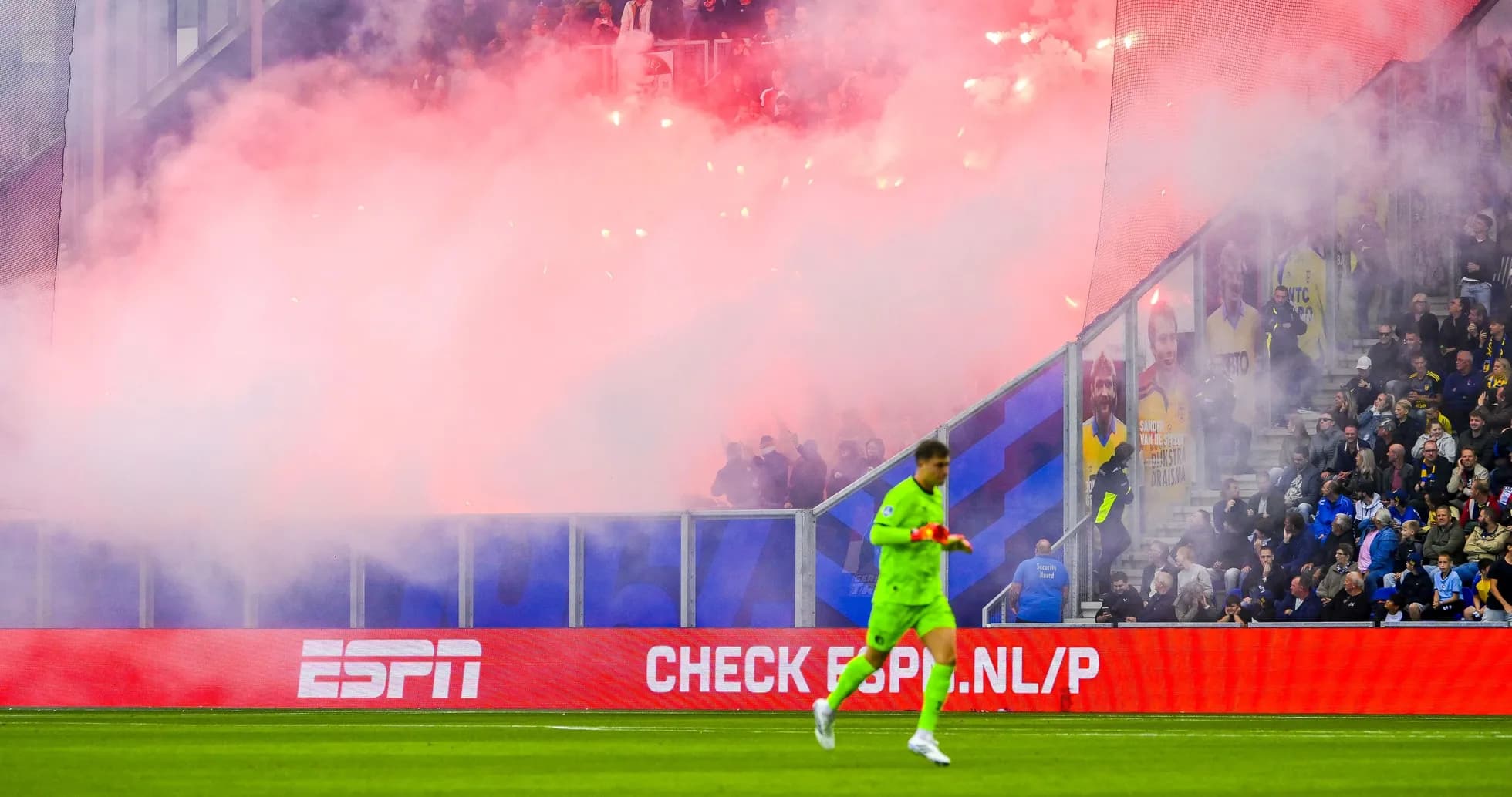 Portero caminando mientras la hinchada genera humo