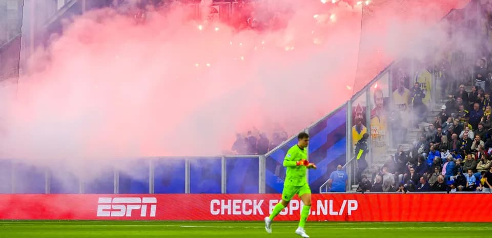 Portero caminando mientras la hinchada genera humo