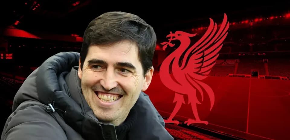 Entrenador sonriendo frente al logo de Liverpool