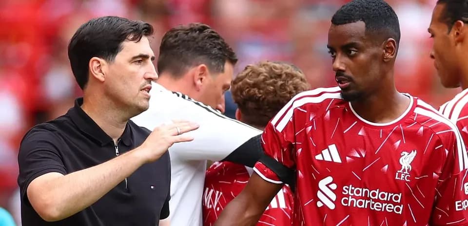 Entrenador hablando con jugador de Liverpool en banquillo
