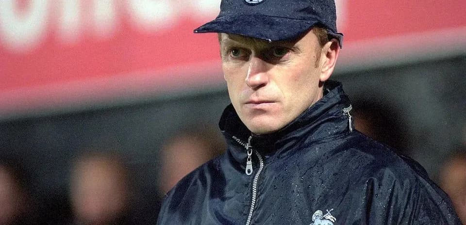 Entrenador de Preston North con gorra y chaqueta