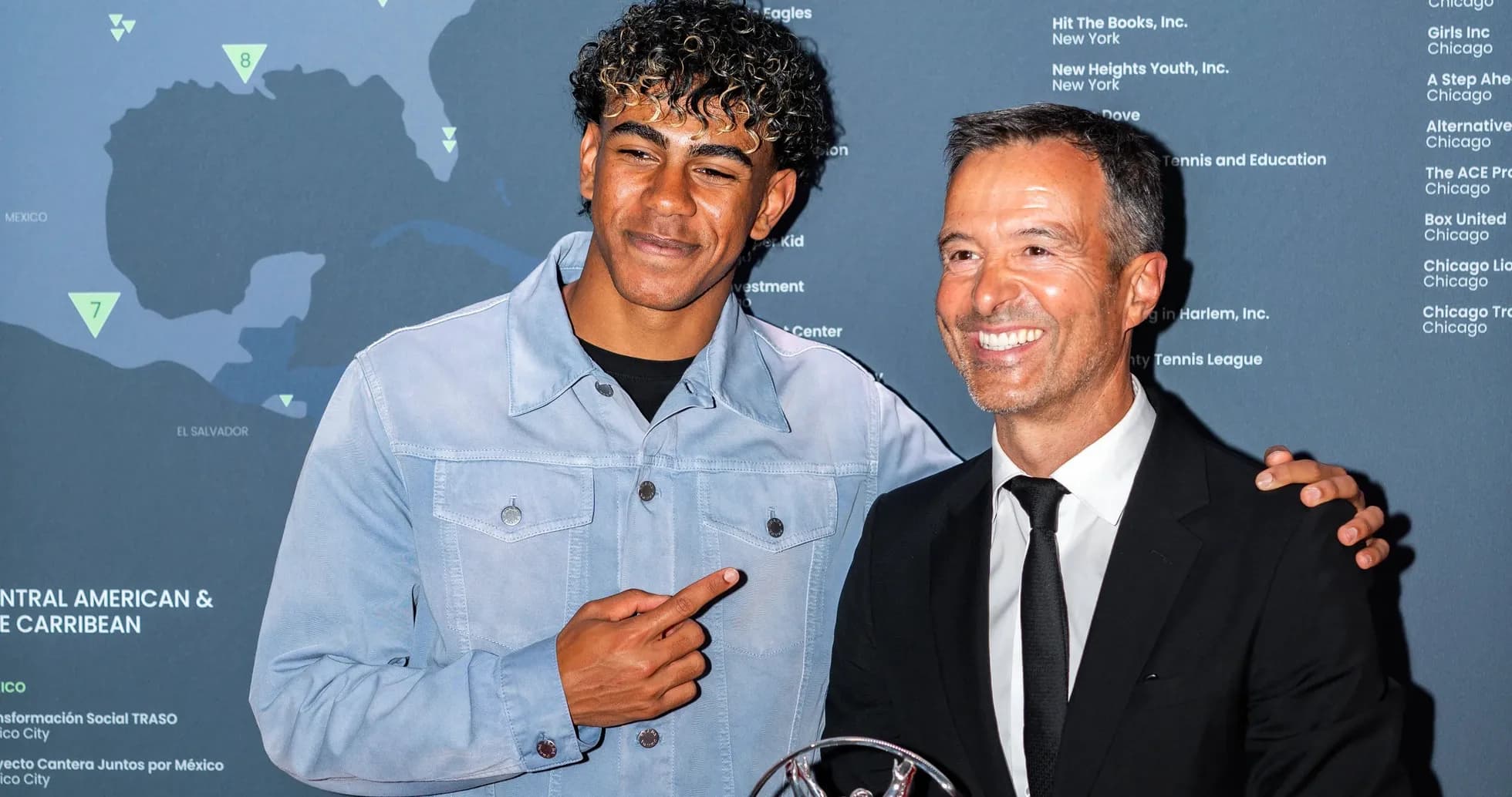 Dos hombres posando juntos en evento con trofeo