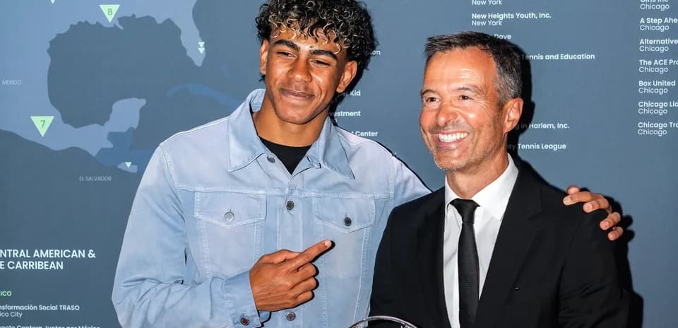 Dos hombres posando juntos en evento con trofeo