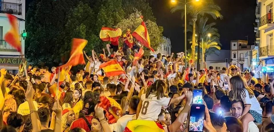Multitud celebrando con banderas españolas en la calle