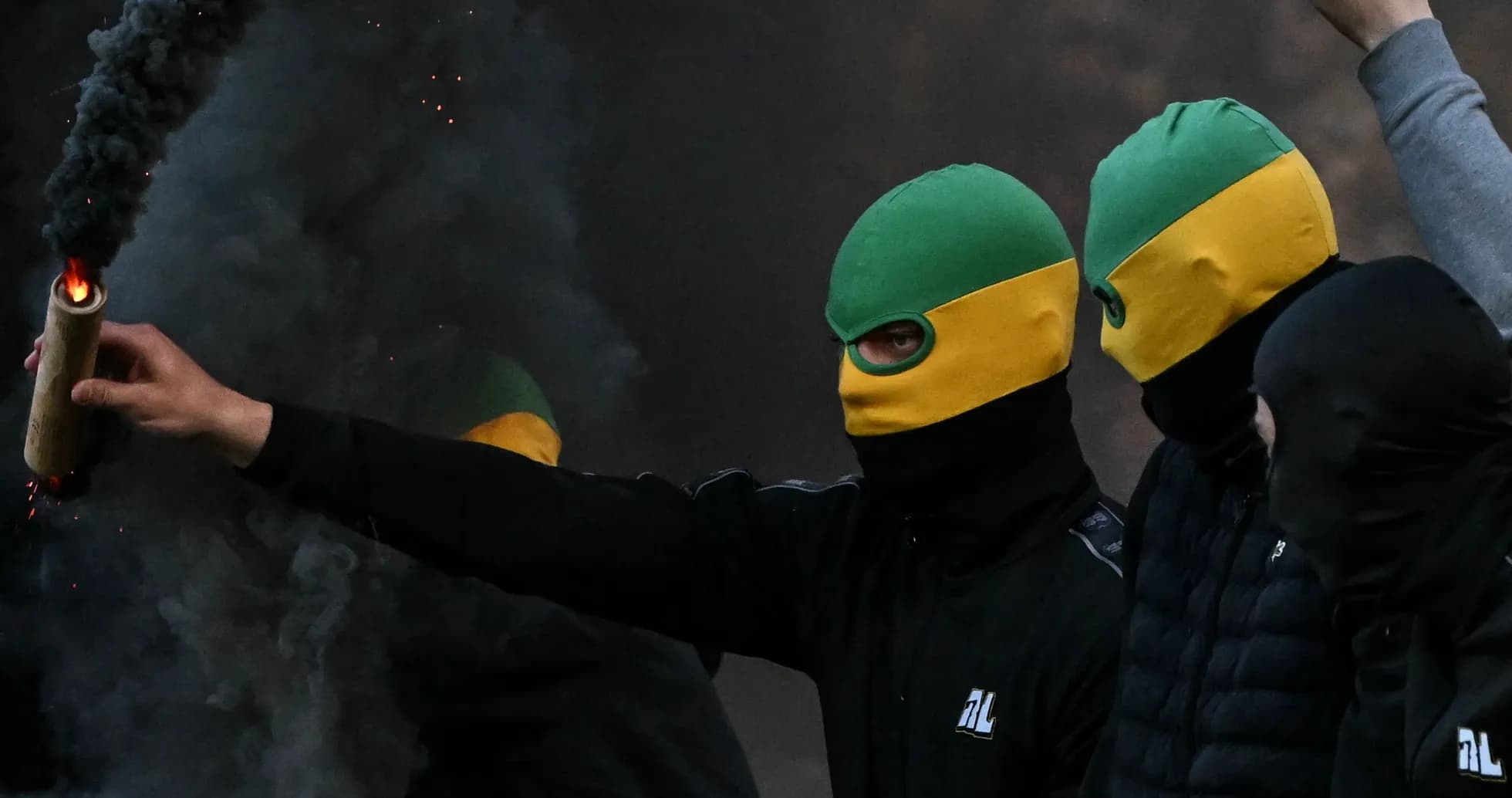 Aficionados con pasamontañas sosteniendo un objeto incendiario