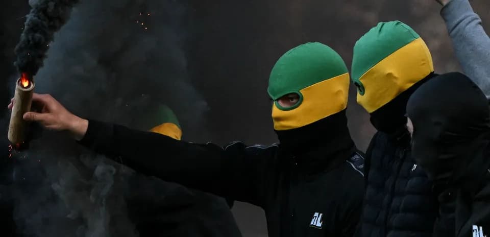 Aficionados con pasamontañas sosteniendo un objeto incendiario