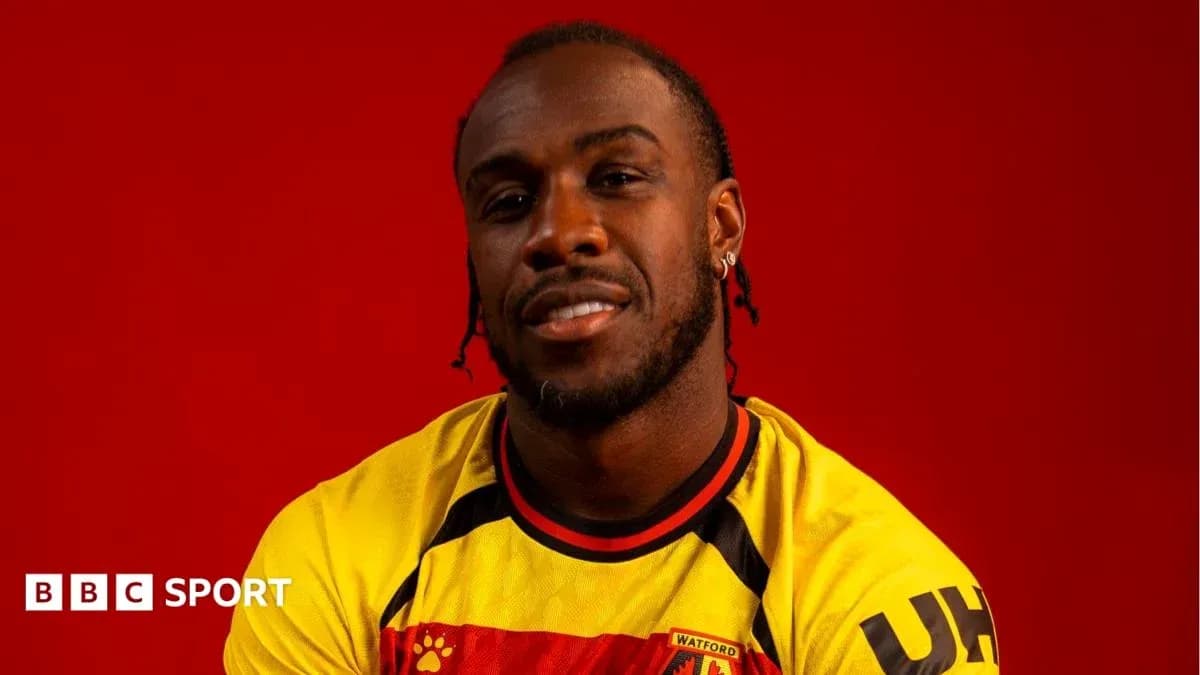 Jugador posando con camiseta de Watford sobre fondo rojo Jugador posando con camiseta de Watford sobre fondo rojo