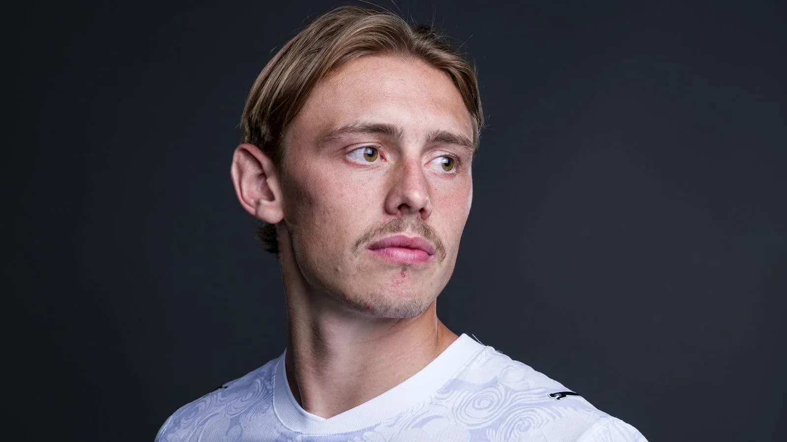 Jugador posando en camiseta blanca con fondo oscuro