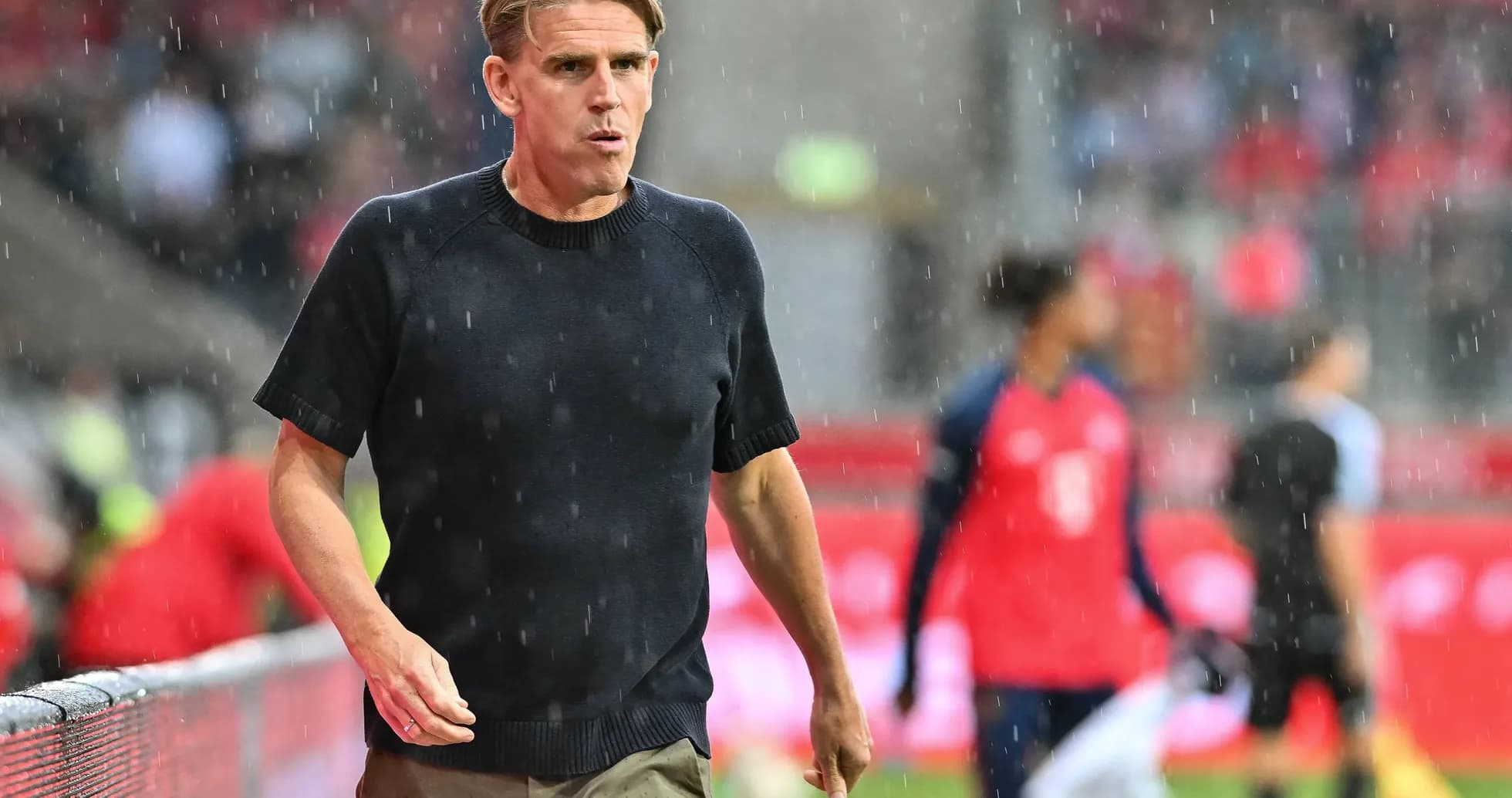 Entrenador caminando en la lluvia durante el partido