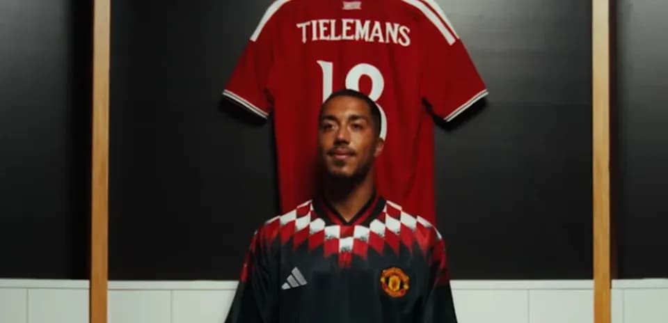 Jugador posando frente a camiseta colgada en vestuario
