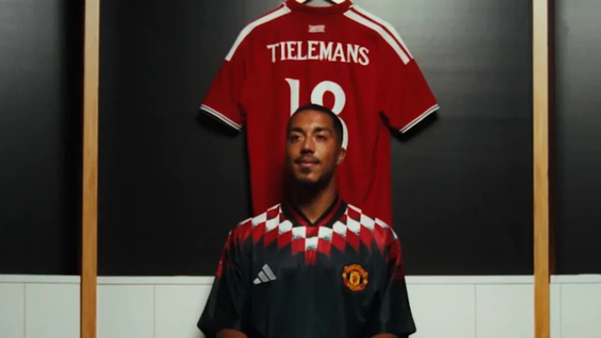 Jugador posando frente a camiseta colgada en vestuario