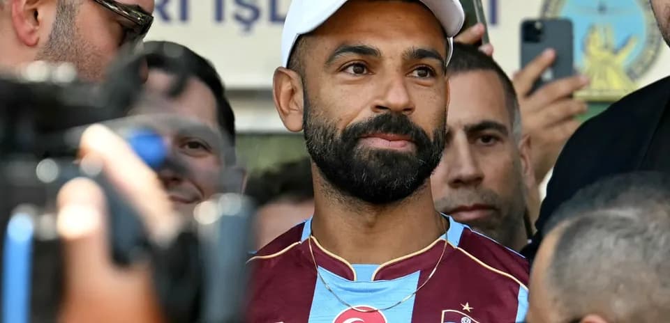 Jugador de fútbol en conferencia de prensa rodeado de medios