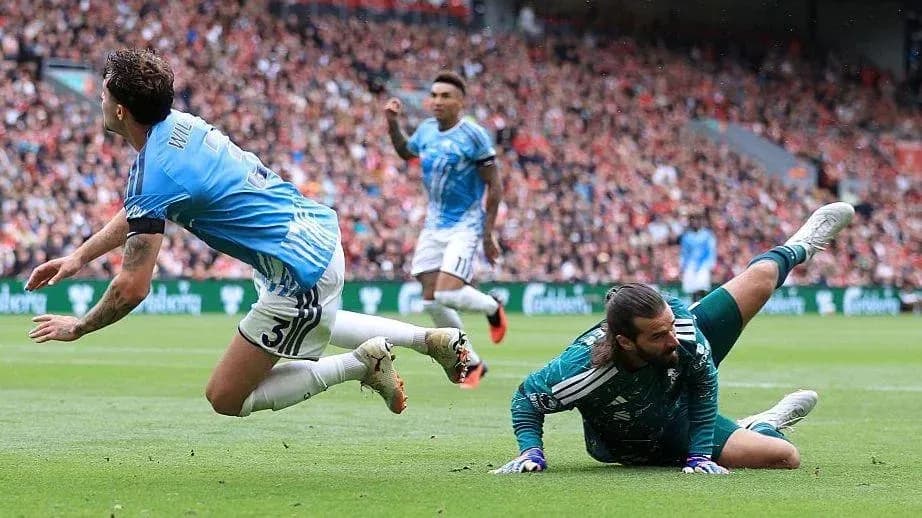 Jugador cae mientras el portero atrapa el balón Jugador cae mientras el portero atrapa el balón