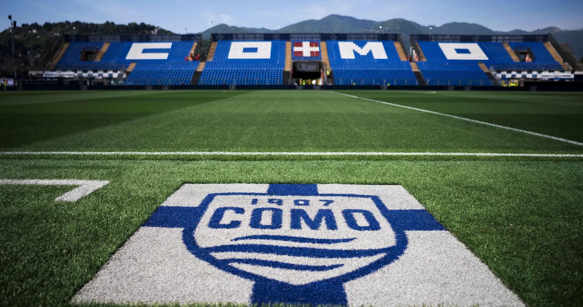 Campo de fútbol con logo de Como 1907 en primer plano Campo de fútbol con logo de Como 1907 en primer plano