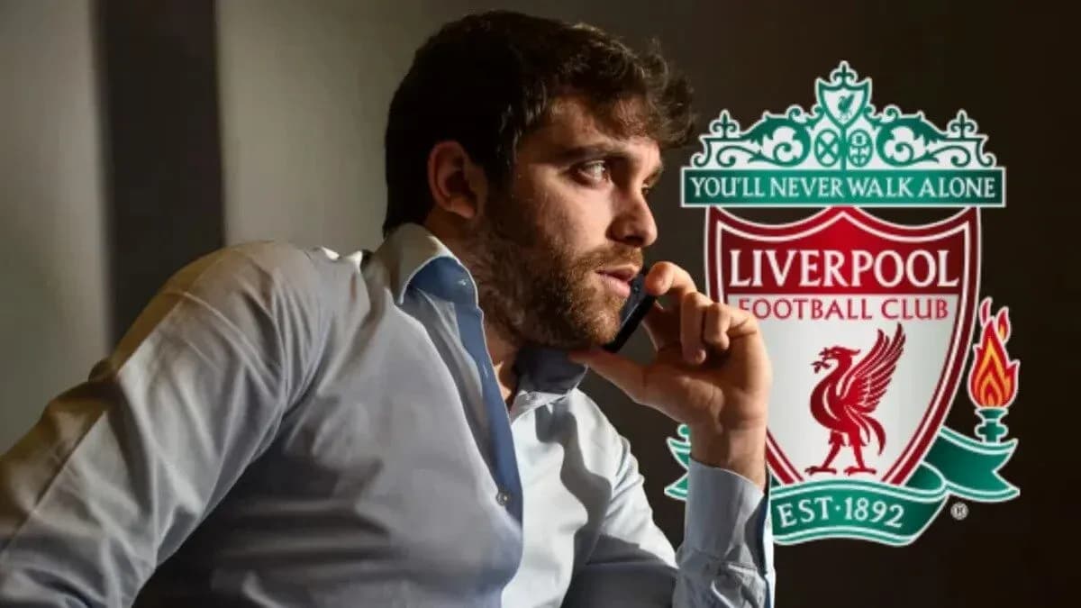 Hombre hablando por teléfono junto al escudo de Liverpool Hombre hablando por teléfono junto al escudo de Liverpool