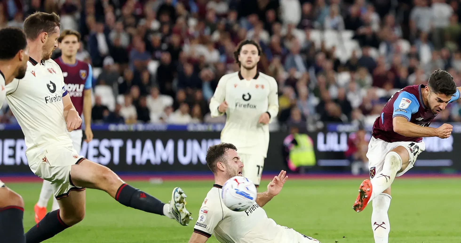 Jugador de West Ham chutando mientras rival cae al suelo Jugador de West Ham chutando mientras rival cae al suelo