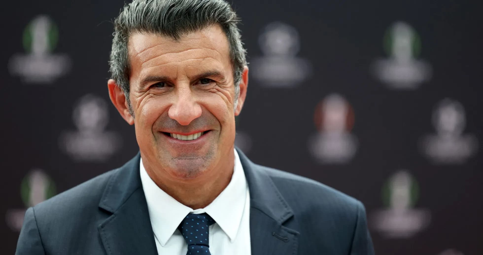 Hombre sonriendo en evento deportivo con fondo oscuro Hombre sonriendo en evento deportivo con fondo oscuro