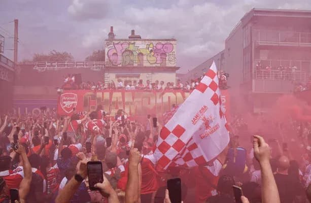 Aficionados de Arsenal celebrando con humo y banderas Aficionados de Arsenal celebrando con humo y banderas