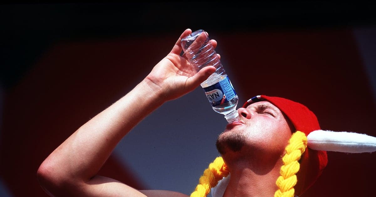 Hombre bebiendo agua de botella en evento deportivo Hombre bebiendo agua de botella en evento deportivo