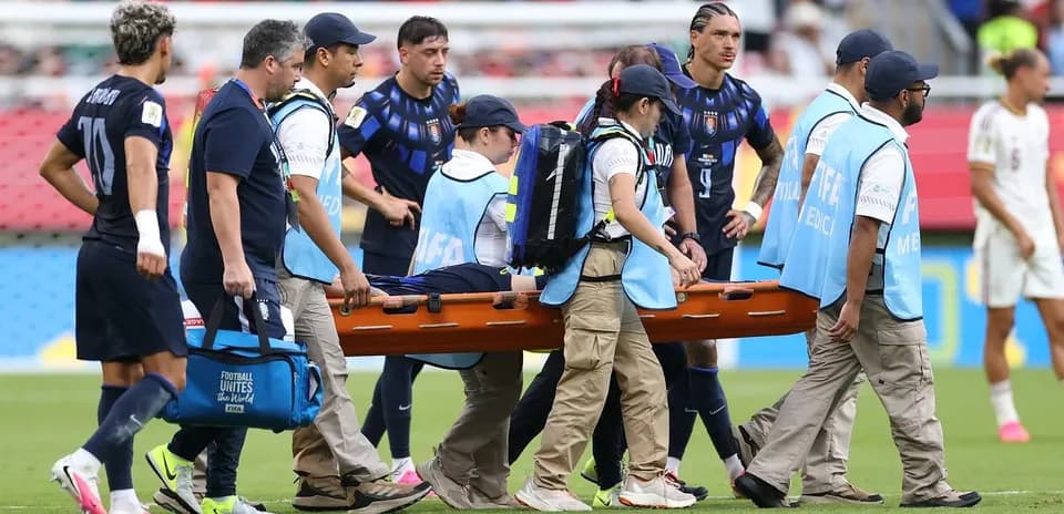 Jugadores y personal médico trasladando a un jugador en camilla Jugadores y personal médico trasladando a un jugador en camilla