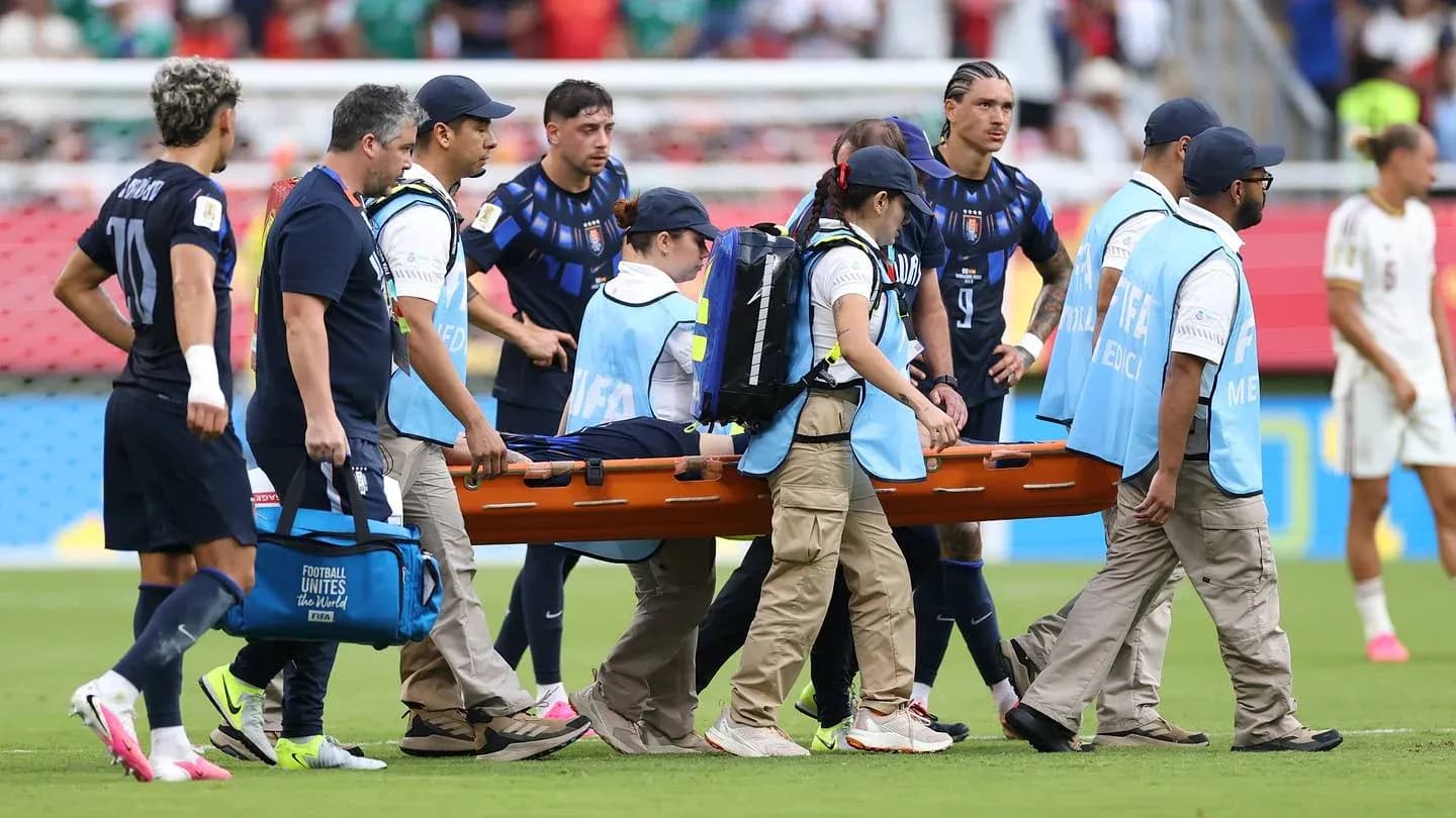 Jugadores y personal médico trasladando a un jugador en camilla Jugadores y personal médico trasladando a un jugador en camilla
